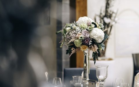 精致玻璃花瓶中插着三枝盛开的粉色百合花，花瓣舒展、花蕊清晰，背景为简洁白色桌面，整体优雅清新